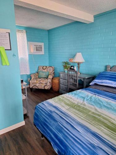a bedroom with blue walls and a bed and a chair at Lake Point Motel in Marblehead