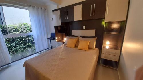 um quarto com uma cama com almofadas amarelas e uma janela em Apenas 5 min das Termas, encantador apto 203 em Piratuba