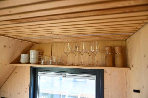 a shelf with glasses and other items on it at Tiny House Pioneer 1 - Green Tiny Spot Schillig in Wangerland