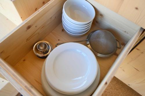 a cabinet with plates and bowls and a spoon at Tiny House Pioneer 3 - Green Tiny Spot Schillig in Wangerland