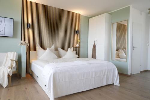 a white bedroom with a large white bed with white pillows at Tief 10 „Meerblick Deck 9“ in Wangerland
