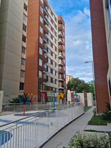 a fence with a playground in front of a building at Oasis Panelero Apartamento Familiar Villeta in Villeta