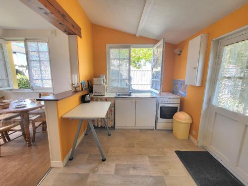 une cuisine avec des murs orange, une table et un comptoir dans l'établissement Maison Authentique: Plage, Commerces et Jardin Clôturé - FR-1-364-33, à Saint-Brévin-les-Pins