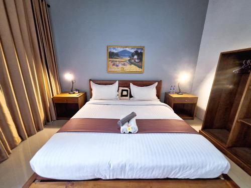 a bedroom with a large white bed with two tables at Novia Guest House Lombok-Tetebatu in Tetebatu