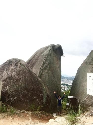 a person standing in front of a large rock at East Villa Shimanami Mukaishima seafront in Onomichi