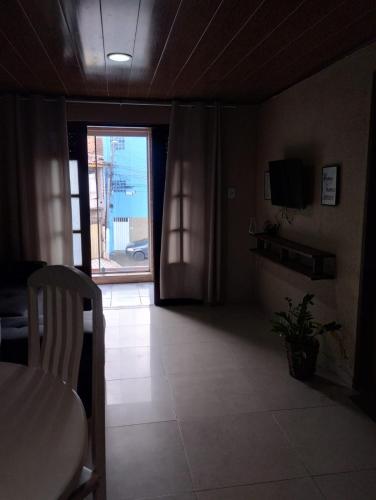 a living room with a table and a door to a window at Na Jatiuca in Maceió