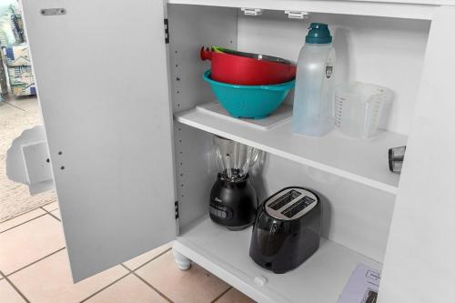 a white cabinet with a bowl and a bottle of milk at Cherry Grove efficiency just steps from the beach in Myrtle Beach