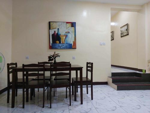 a dining room with a table and chairs and a painting at T&J Guest House in Rauis
