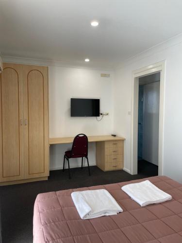 a bedroom with a bed and a desk and a television at Homestead Motel in Dubbo