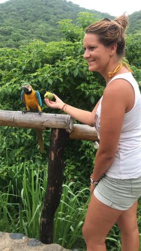 a woman standing next to a parrot on a fence at HOSTAL MIRADOR dentro del parque tayrona in El Zaino