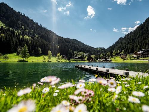 un pont sur un lac avec des fleurs au premier plan dans l'établissement Charmant 3 pièces avec balcon, proche centre et remontées mécaniques, Châtel - FR-1-676-35, à Châtel