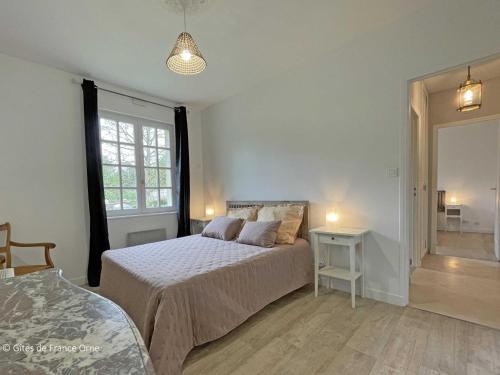 a bedroom with a bed and a table and a window at Maison confortable dans le Perche avec jardin et animaux admis - FR-1-497-205 in Longny-au-Perche