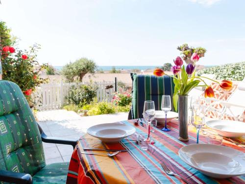 - une table avec des assiettes, des verres à vin et des fleurs dans l'établissement Charmant Pavillon avec 2 Terrasses et Parking Privé à Saint Pierre la Mer - FR-1-409-268, à Fleury