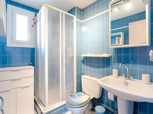 La salle de bains est pourvue de carrelage bleu, de toilettes et d'un lavabo. dans l'établissement Charmant Pavillon avec 2 Terrasses et Parking Privé à Saint Pierre la Mer - FR-1-409-268, à Fleury