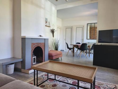 un salon avec une cheminée et une télévision dans l'établissement Maison confort, 3 chambres, plage à 2 pas, jardin privé sans vis-à-vis, équipements modernes. - FR-1-788-12, à Merville-Franceville-Plage