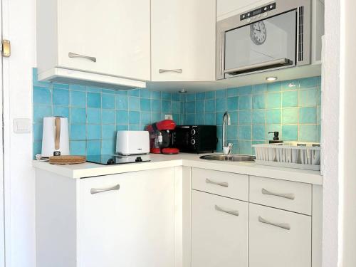 une cuisine avec des placards blancs et du carrelage bleu dans l'établissement Appartement Climatisé 2 Pièces + Coin Nuit, Proche Plage et Commerces, 4 Couchages, Le Lavandou - FR-1-251-829, au Lavandou