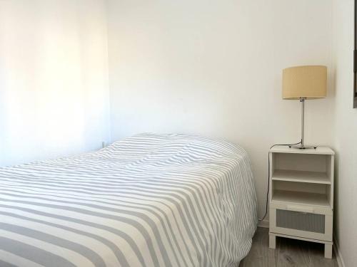 - une chambre blanche avec un lit et une lampe dans l'établissement Appartement Climatisé 2 Pièces + Coin Nuit, Proche Plage et Commerces, 4 Couchages, Le Lavandou - FR-1-251-829, au Lavandou