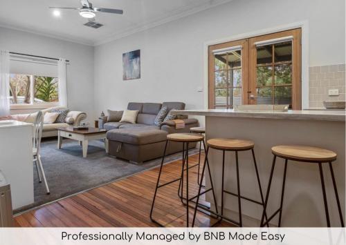 a kitchen and living room with a couch and a bar at Hayes Corner Cottage - Short Drive to CBD, Private in North Wagga