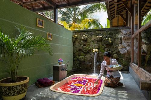 a woman is making a large pool of red flowers at Arkamara Dijiwa Ubud in Ubud