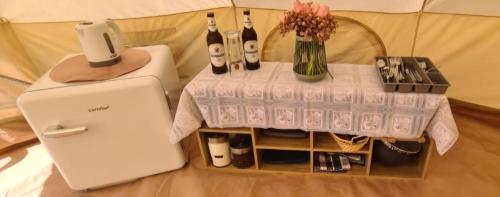 uma mesa com garrafas de vinho e um frigorífico em Tipi Camping in der Mecklenburgischen Seenplatte em Carpin