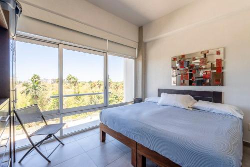 a bedroom with a bed and a chair and a large window at Nayarit Coastal Retreat New Luxury Haven in Nuevo Vallarta 