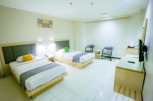 een hotelkamer met 2 bedden en 2 stoelen bij Merpati Hotel in Pontianak