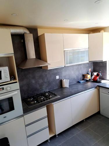 une cuisine avec des armoires blanches et un four à plaques de cuisson dans l'établissement Polat, à Lèves