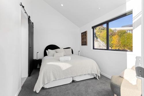 Un dormitorio blanco con una cama y una ventana. en Absolute Lakefront House, en Taupo
