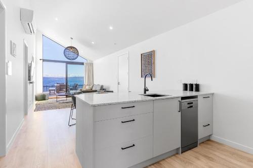 a kitchen with white cabinets and a large window at Absolute Lakefront House in Taupo