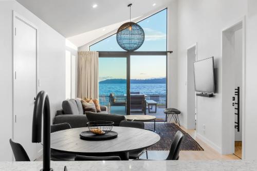 a living room with a table and a view of the ocean at Absolute Lakefront House in Taupo