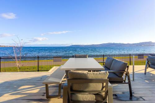 a table and chairs on a patio overlooking the ocean at Absolute Lakefront House in Taupo