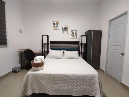 Un dormitorio con una cama blanca con una cesta. en La casita de Gazcue, en Santo Domingo
