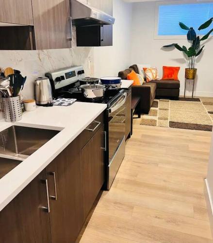a kitchen with a stove and a living room at B19 Modern Stylish 2bed Basement Suite in Edmonton