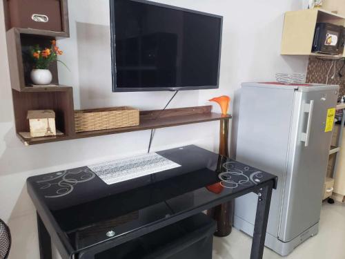 a desk with a computer and a television on a wall at grass residences tower2 21Floor in Manila