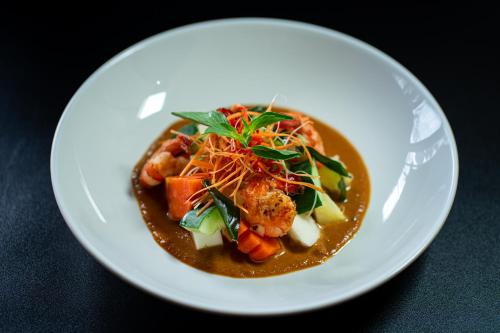a white plate with a bowl of food on a table at d'kamala by Prasi in Ubud