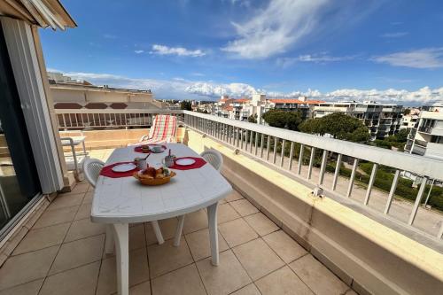 une table blanche et des chaises sur un balcon avec vue dans l'établissement LE MATHILDE - Appart 1 chambre Vue dégagée proche de la plage avec parking, au Grau-du-Roi