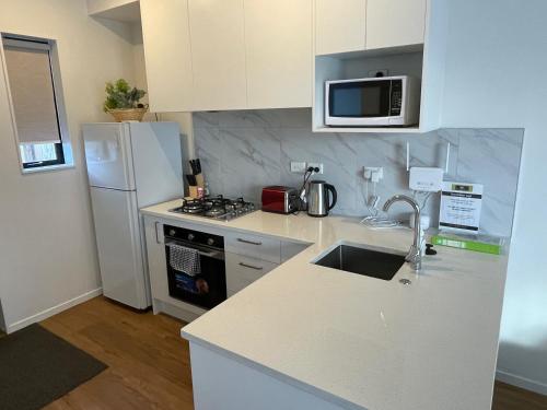 a kitchen with a white refrigerator and a counter top at Flat Bush Holiday Accomodation in Auckland