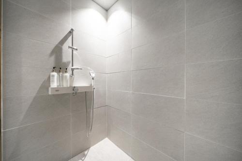 y baño con ducha de azulejos blancos. en Hotel LeeSunDeok en Busan