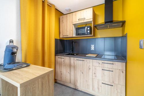 une cuisine avec des placards en bois et un mur jaune dans l'établissement Cosy apartment with pool, à Toulouse