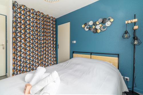une chambre avec un lit blanc avec un mur bleu dans l'établissement Cosy apartment with pool, à Toulouse