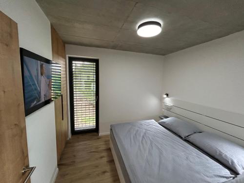 a bedroom with a bed and a flat screen tv at Retro chaty Soběšky in Horní Soběšovice