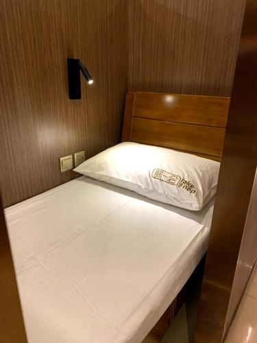 Chengdu Airport Take A Nap Capsule Hotel（T2） في تشنغدو: سرير في غرفة صغيرة بملاءات بيضاء