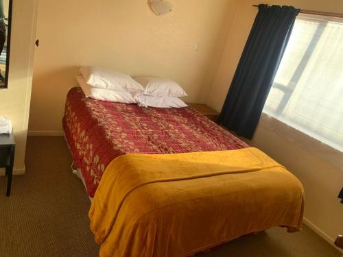a hotel room with a bed with a window at Aaron Court Motel in Timaru