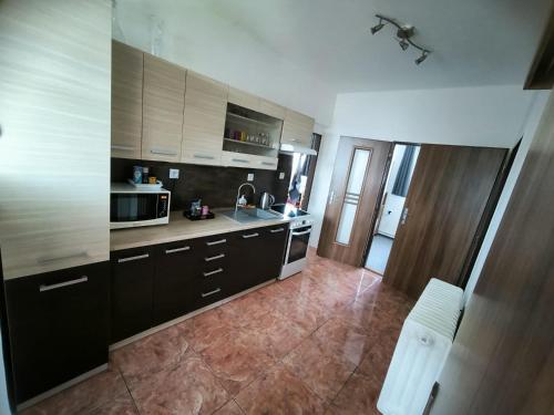 a kitchen with black cabinets and a tile floor at Apartmán u potoka in Kestřany