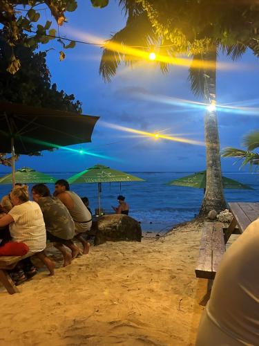 a group of people sitting on a bench on the beach at Aroa Beachside Resort in Rarotonga