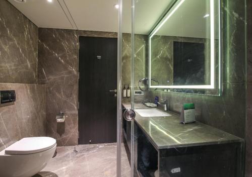 a bathroom with a toilet and a sink and a mirror at Essentia Premier Hotel Pune Wakad in Pune