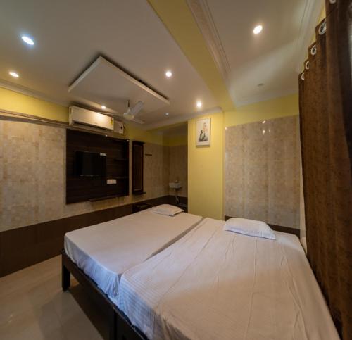 a bedroom with a large bed and a tv at JR Lodge in Velankanni