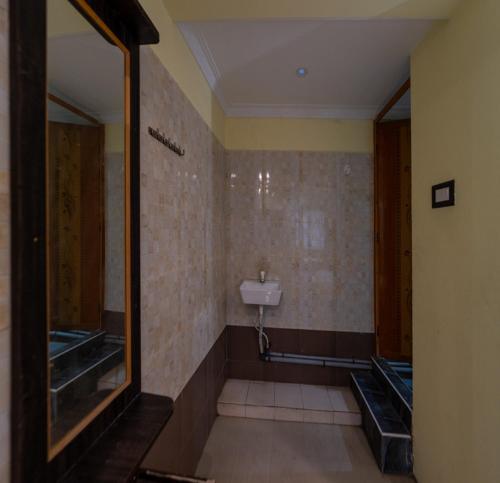 a bathroom with a urinal and a mirror at JR Lodge in Velankanni