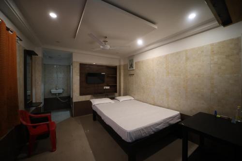a bedroom with a bed and a red chair at JR Lodge in Velankanni