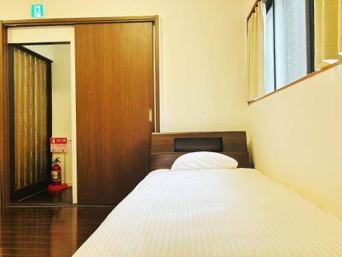 Un dormitorio con una cama y una puerta de madera. en Kokoro no sato・Ume, en Kioto